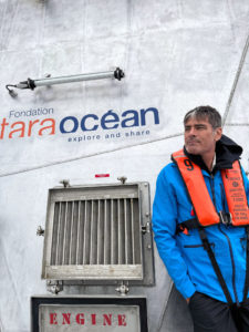 Un homme avec un gilet de sauvetage devant une embarcation